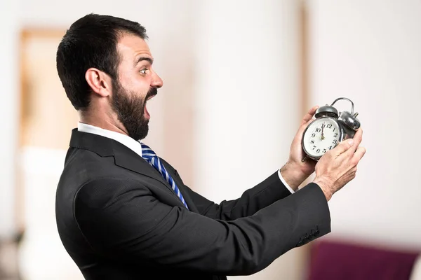 Jonge zakenman houden een antieke klok op witte achtergrond — Stockfoto