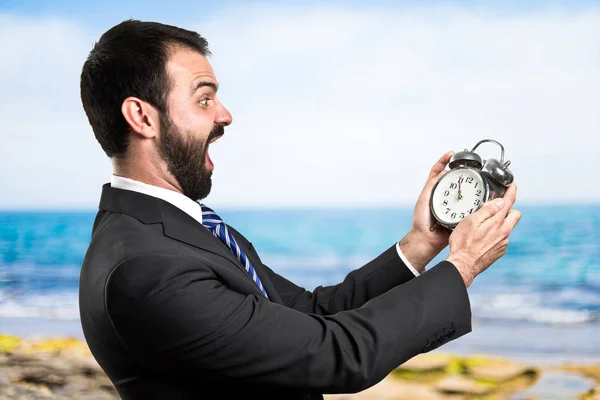 Junger Geschäftsmann hält eine antike Uhr vor weißem Hintergrund — Stockfoto