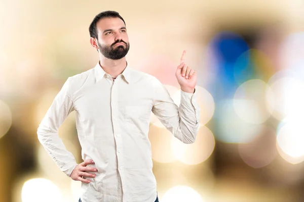 Joven apuntando hacia arriba sobre fondo blanco — Foto de Stock