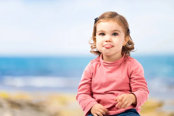 Söt baby flicka sticker ut tungan över vit bakgrund — Stockfoto