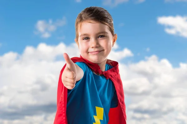 Chica vestida como superhéroe con el pulgar hacia arriba en backgrou desenfocado — Foto de Stock