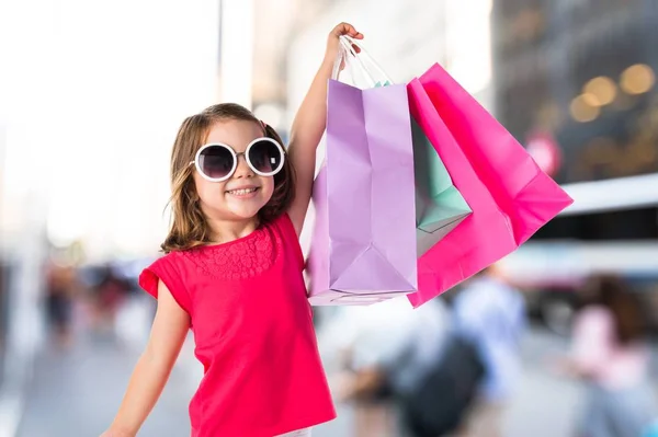 Lány sok bevásárló táskák, a céltalan háttér — Stock Fotó
