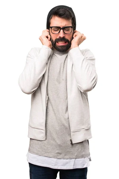 Hipster mies peittää korvansa valkoisella taustalla — kuvapankkivalokuva