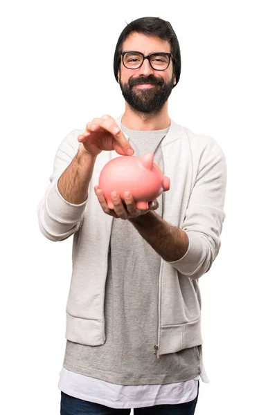 Happy Hipster man holding a piggybank on white background — Stock Photo, Image
