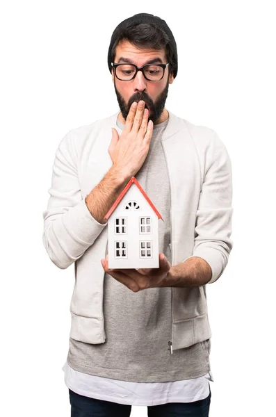 Sorprendido Hipster hombre sosteniendo una pequeña casa sobre fondo blanco — Foto de Stock