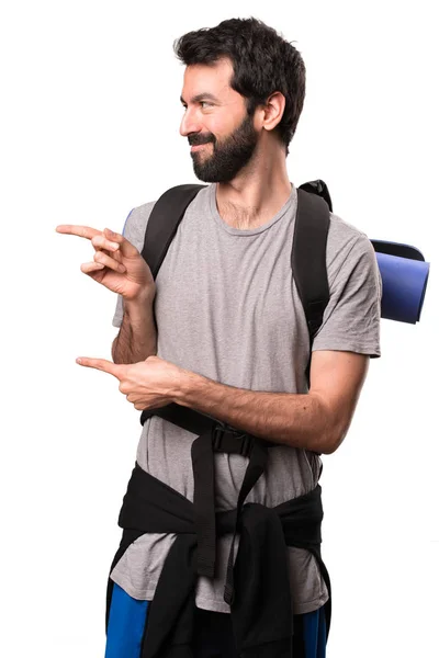 Przystojny backpacker wskazując boczne na białym tle — Zdjęcie stockowe