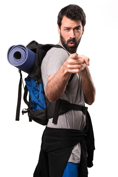 Handsome backpacker pointing to the front on white background — Stock Photo, Image