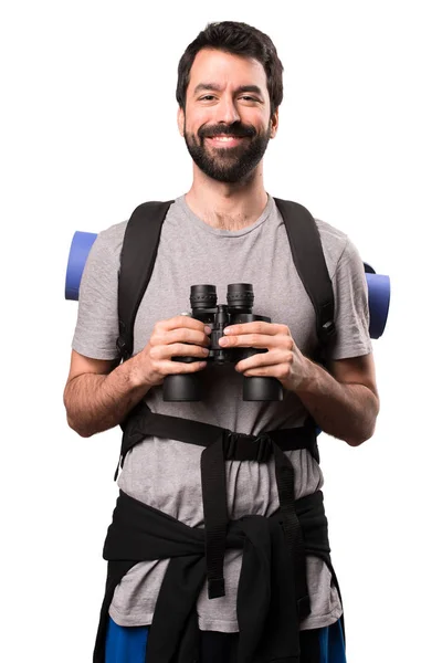 Gelukkig knap backpacker met een verrekijker op witte achtergrond — Stockfoto