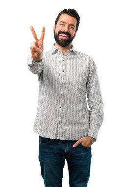 Gülümseyen ve zafer işaret gösteren sakallı yakışıklı adam