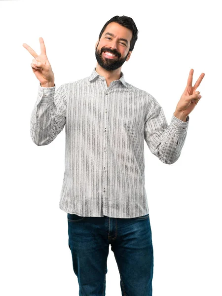 Bonito homem com barba sorrindo e mostrando sinal de vitória — Fotografia de Stock