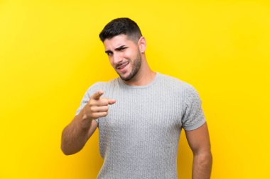 Izole sarı arka plan noktaları üzerinde genç yakışıklı adam size parmak