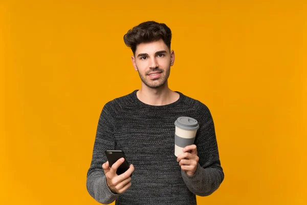 Jovem Sobre Fundo Isolado Segurando Café Para Levar Celular — Fotografia de Stock