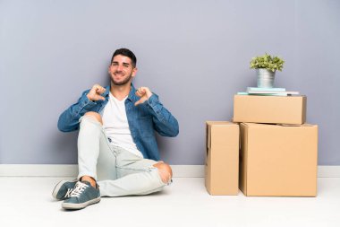 Yakışıklı genç adam kutuları arasında yeni bir evde hareketli gururlu ve kendini memnun