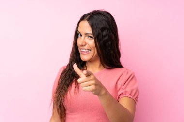 Izole pembe arka plan üzerinde genç kadın size parmak