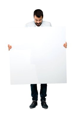 Boş bir afişini izole beyaz arka plan üzerinde tutarak sakallı yakışıklı adam tam uzunlukta atış