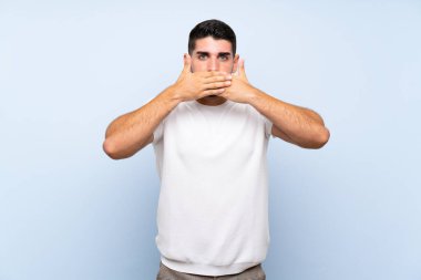Beyaz yakışıklı adam elleriyle ağız kapsayan izole mavi arka plan üzerinde