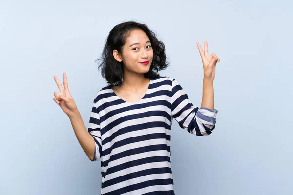 Asiática Joven Mujer Sobre Aislado Azul Fondo Mostrando Victoria Signo —  Fotos de Stock