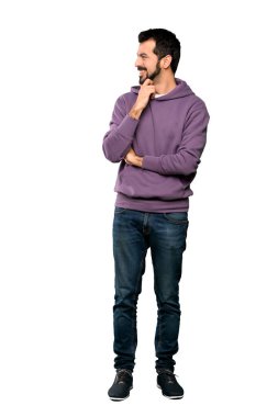 Sweatshirt 'lü yakışıklı bir adamın izole edilmiş beyaz arkaplana bakarken tam boy fotoğrafı.