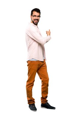 Sakallı yakışıklı bir adam izole edilmiş beyaz arka planı işaret ediyor.