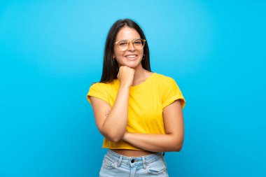 Gözlüklü ve gülümseyen, soyutlanmış mavi bir geçmişi olan genç bir kız.