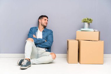 Yeni evinde kutular arasında dolaşan yakışıklı genç adam gülüyor