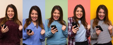 Telefonlu bir kadın takımı zafer pozisyonunda.