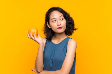 Asyalı genç kadın bir portakal tutan