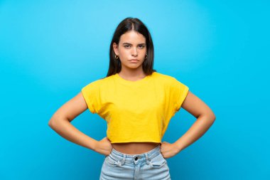 Genç kız soyutlanmış mavi arka planda kızgın.