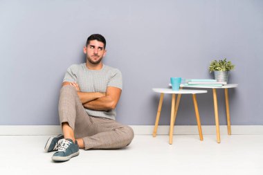 Genç yakışıklı bir adam yerde oturmuş bir fikir düşünüyor.