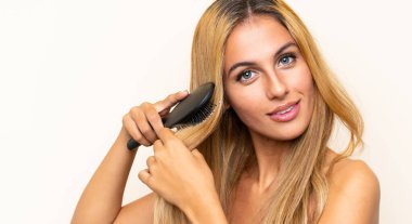 Izole arka plan üzerinde saç tarak ile genç sarışın kadın