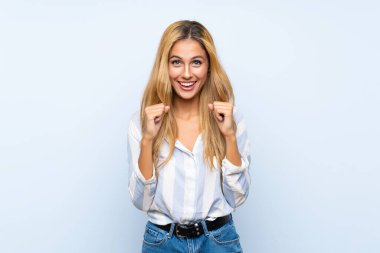 Soyutlanmış mavi arka planda genç sarışın kadın galibiyeti kutluyor.