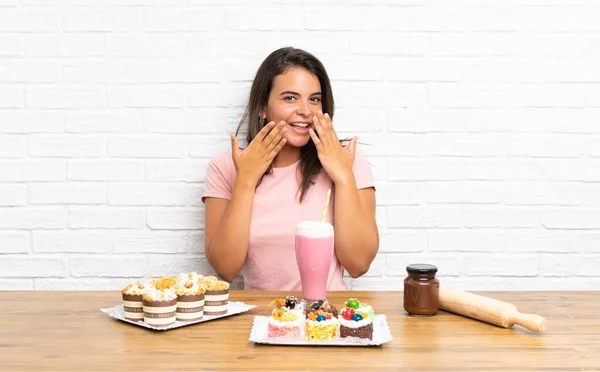 Junges Mädchen Mit Vielen Verschiedenen Mini Kuchen Mit Überraschendem Gesichtsausdruck — Stockfoto