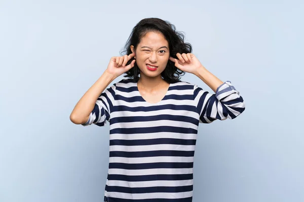Азиатская Молодая Женщина Изолированном Голубом Фоне Расстроен Покрывает Уши — стоковое фото