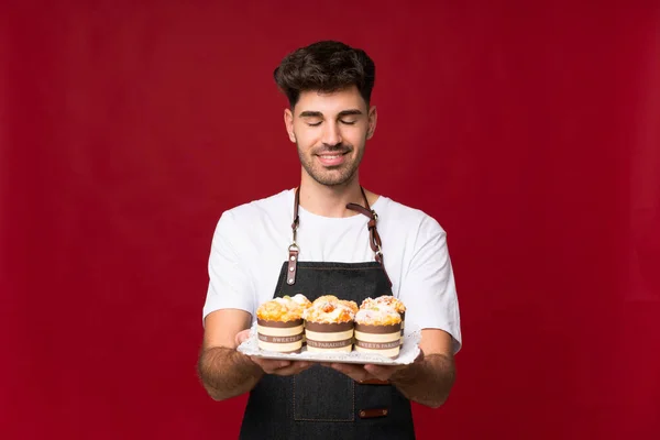 Joven Sobre Fondo Aislado Sosteniendo Mini Pasteles — Foto de Stock