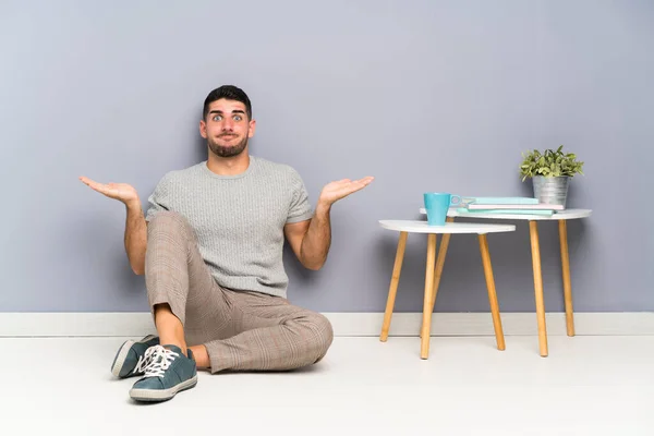 Jovem Homem Bonito Sentado Chão Com Dúvidas Com Expressão Facial — Fotografia de Stock