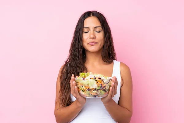 Young woman with salad over isolated wall