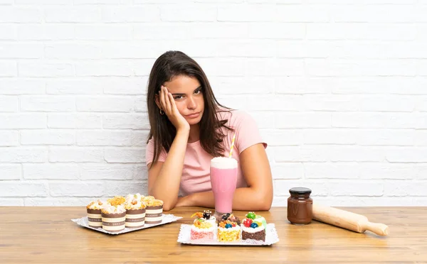 Chica Joven Con Montón Diferentes Mini Pasteles Infeliz Frustrado —  Fotos de Stock