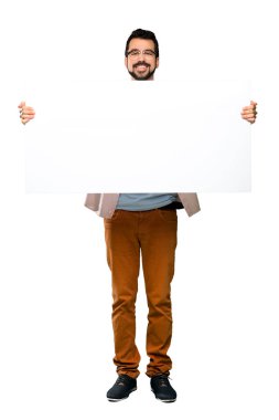 Boş bir afişini izole beyaz arka plan üzerinde tutarak sakallı yakışıklı adam tam uzunlukta atış