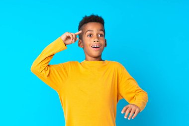 Afro-Amerikalı çocuk mavi arka planda çözümü bulmaya çalışıyor.