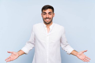 Izole mavi arka plan üzerinde sakallı yakışıklı adam gülümseyerek