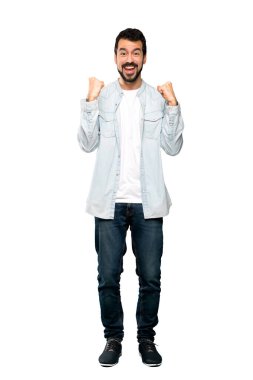 Sakallı, yakışıklı bir adamın izole edilmiş beyaz arka plana karşı kazandığı galibiyeti kutlarken tam boy fotoğrafı.