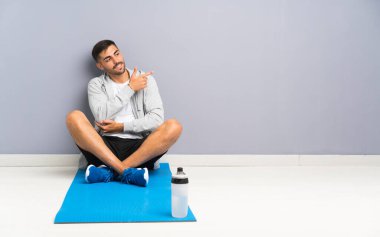 Spor adam yan parmak işaret eden bir yerde oturan