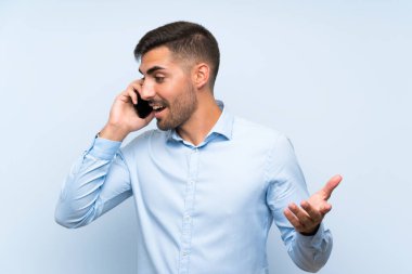 Izole mavi duvar üzerinde cep ile genç yakışıklı adam