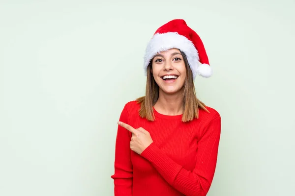 Girl Christmas Hat Isolated Green Background Pointing Finger Side — ストック写真