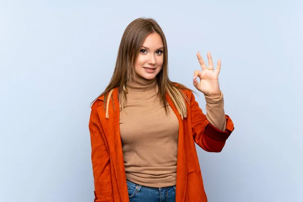 Дівчинка Підліток Пальто Над Ізольованим Синім Тлом Показує Знак Пальцями — стокове фото