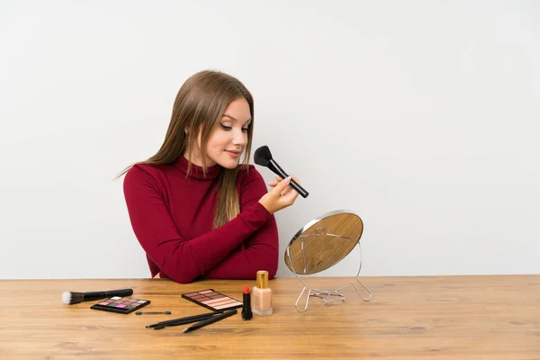Adolescente avec palette de maquillage et cosmétiques dans une table — Photo