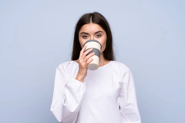 Tânăra Femeie Peste Fundal Albastru Izolat Care Deține Bea Cafea — Fotografie, imagine de stoc