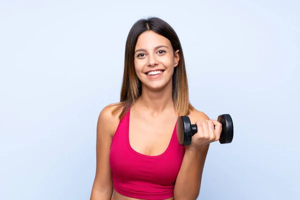 Mujer Deportiva Joven Sobre Fondo Azul Aislado Haciendo Levantamiento Pesas —  Fotos de Stock