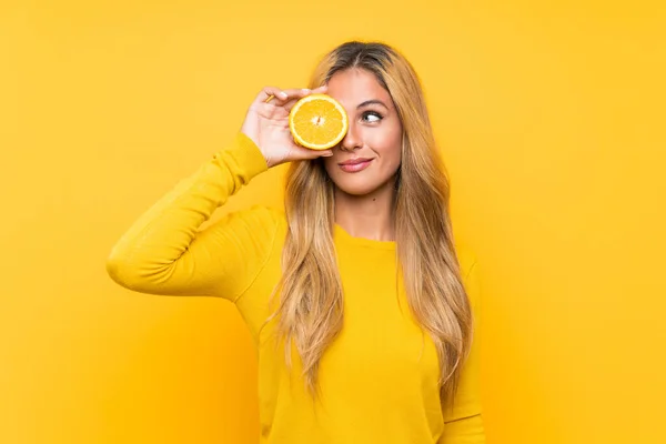 Mujer Rubia Joven Sosteniendo Fondo Naranja Sobre Amarillo — Foto de Stock