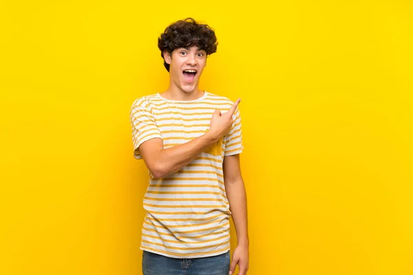Junger Mann Über Isolierte Gelbe Wand Überrascht Und Zeigt Zur — Stockfoto